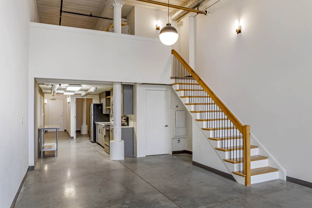 a room with a staircase and a white wall and a ceiling light at Highland Mill Lofts, Charlotte, NC