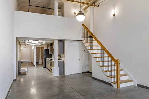 a room with a staircase and a white wall and a ceiling light at Highland Mill Lofts, Charlotte, NC