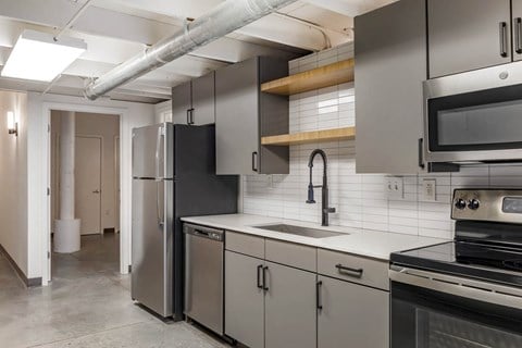 a kitchen with stainless steel appliances and white counter tops at Highland Mill Lofts, North Carolina