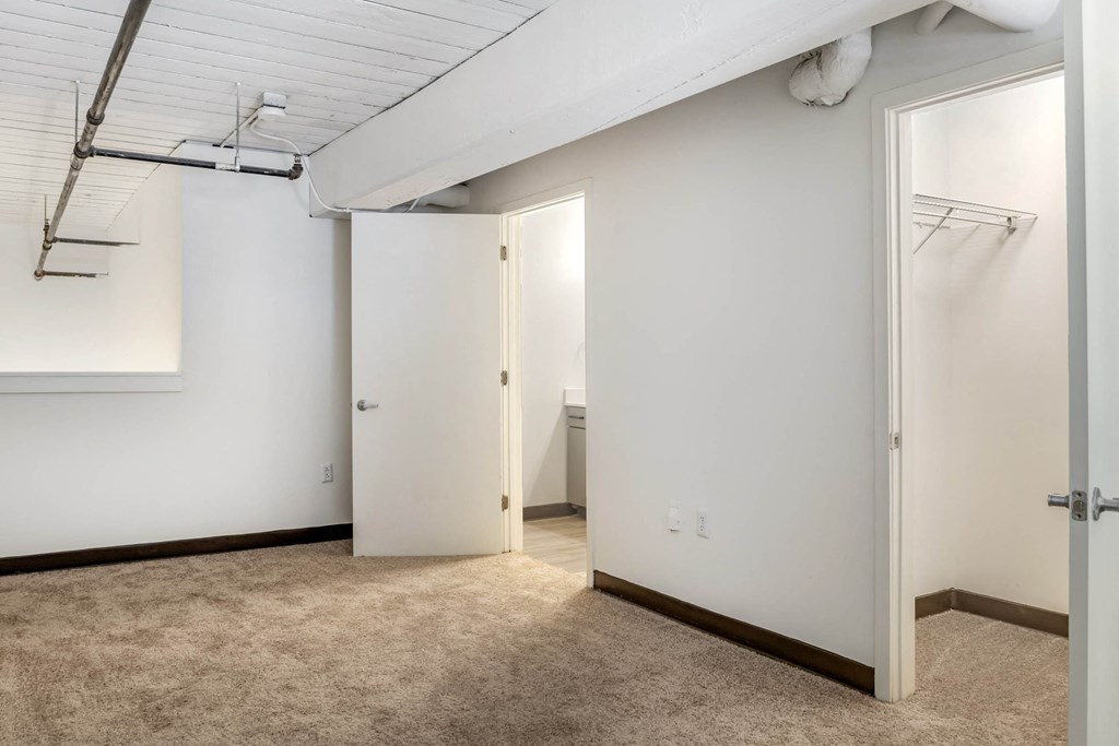an empty room with white walls and a door to a closet at Highland Mill Lofts, Charlotte, NC
