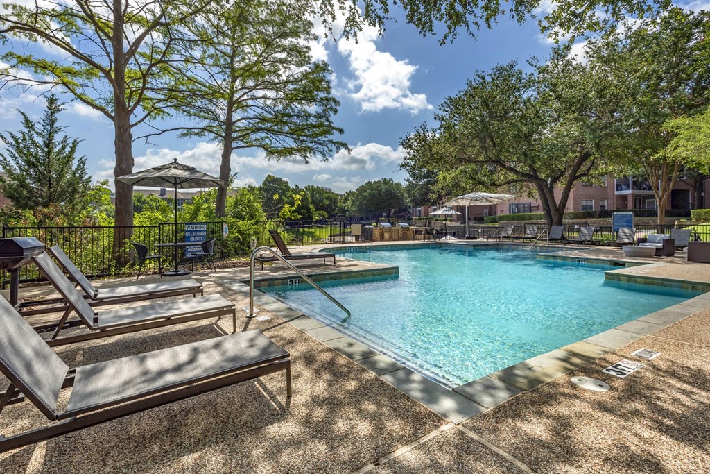 a resort style swimming pool with lounge chairs and trees at Lakeshore at Preston, Plano, TX