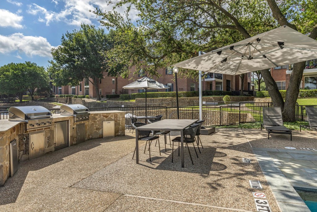 a patio with a table and chairs and a grill