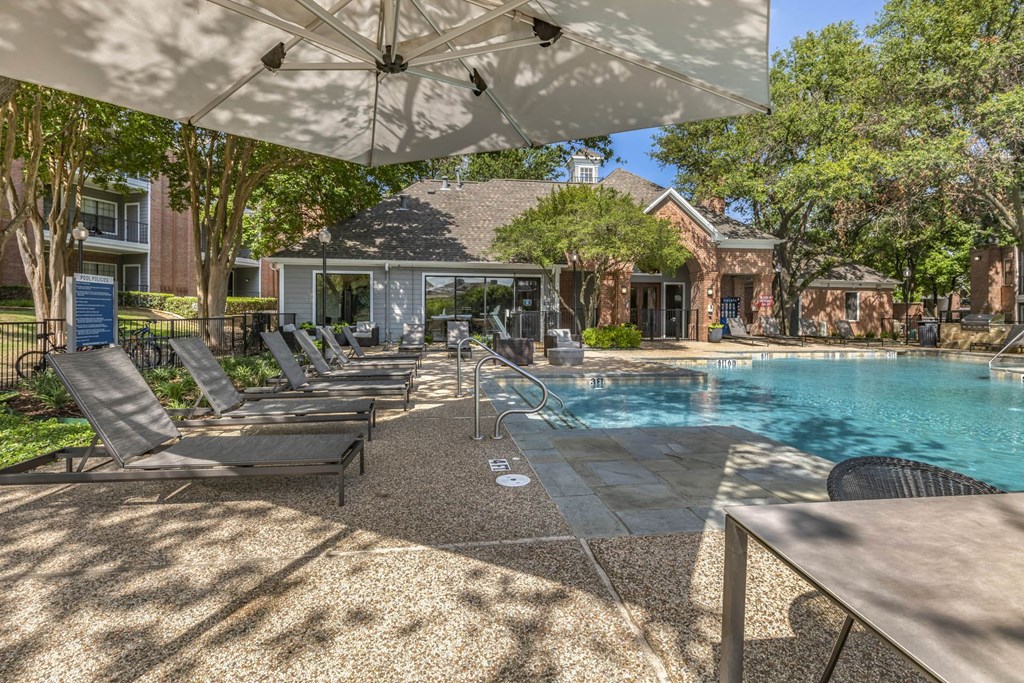 a swimming pool with chairs and umbrellas in front of a house at Lakeshore at Preston, Plano, 75093