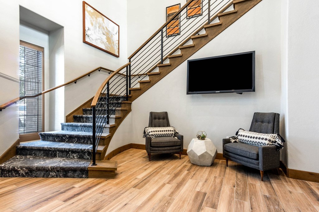 a living room with a staircase and a tv on the wall at The links at Plum Creek Apartments, Castlerock