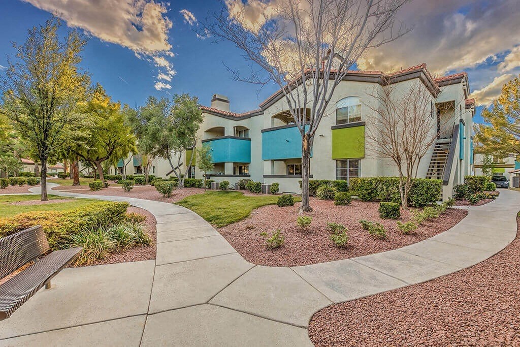 an exterior view of a building with a sidewalk and benches at Mirasol Apartments, Las Vegas, Nevada