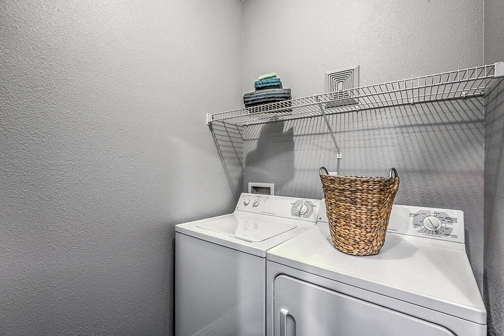 a washer and dryer in a laundry room with a rack on the wall at Mirasol Apartments, Las Vegas, Nevada