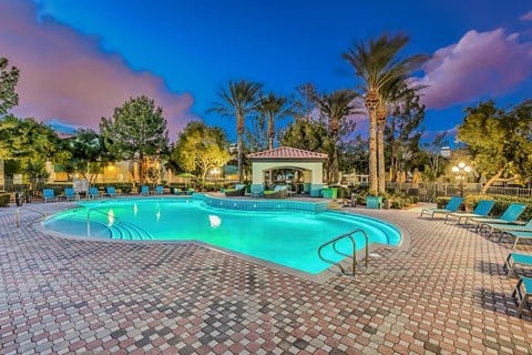 a swimming pool with chairs and trees around it at night at Mirasol Apartments, Nevada, 89119