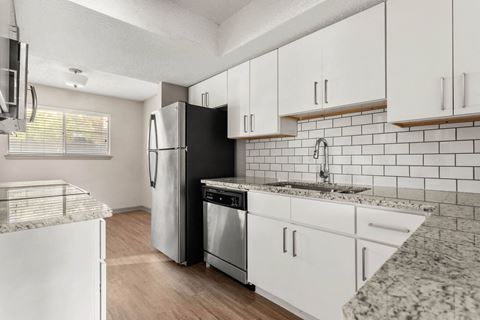 a kitchen with white cabinets and a stainless steel refrigerator at South Lamar Village, Texas, 78704