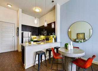 a kitchen with a bar and stools and a round table at South Side Flats, Dallas, TX