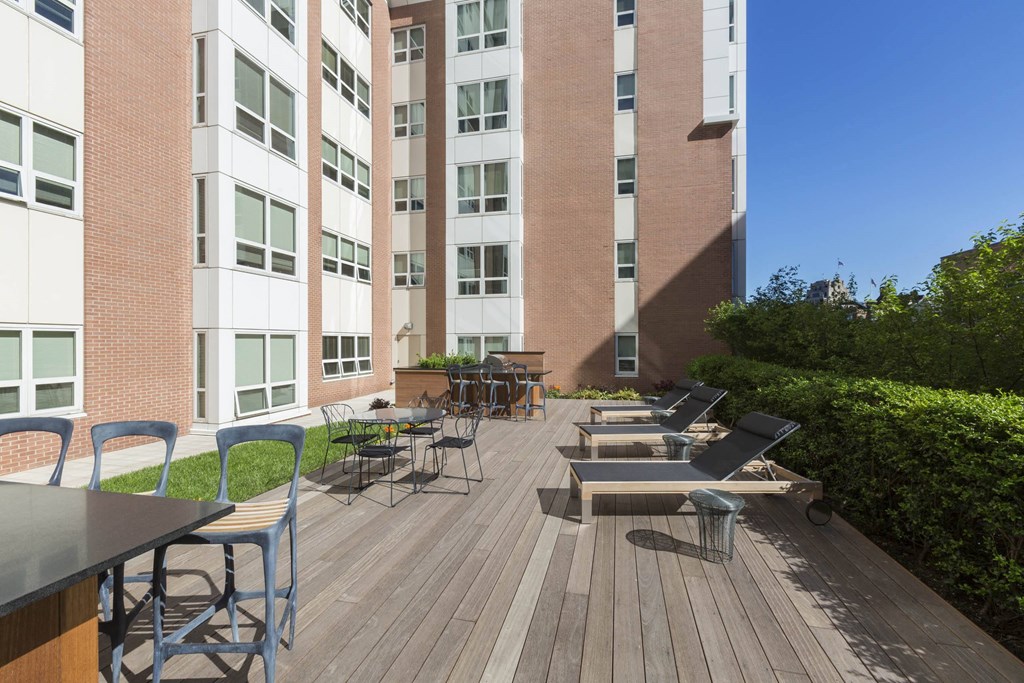 a large patio with tables and chairs in front of an apartment building at Amelia, Quincy, Massachusetts