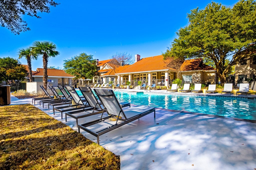 a swimming pool with deck chairs next to a house