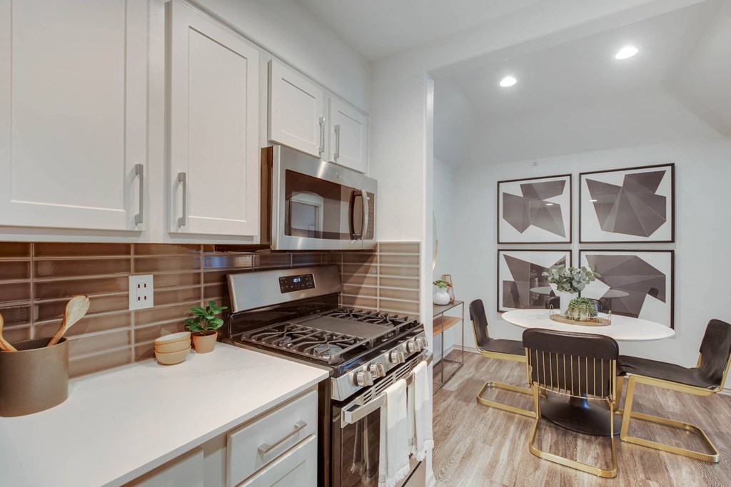a kitchen with white cabinets and a table and a stove