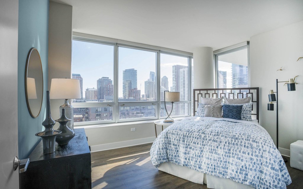 a bedroom with a bed and a view of the city at The Elle Apartments, Chicago, Illinois