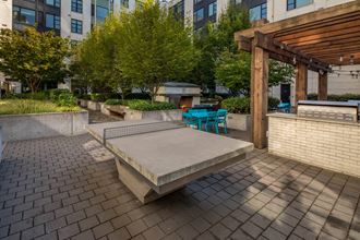 an outdoor seating area with a concrete ping pong table and a wooden pergola at The Parker, Oregon, 97209