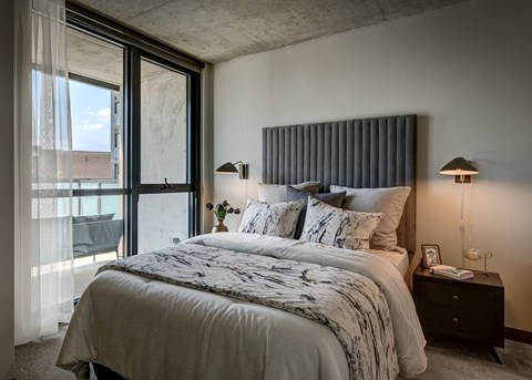 A bedroom with a large bed and a window with curtains. at The Mason Apartments, Chicago, Illinois