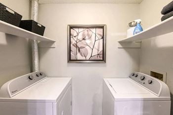 a white laundry room with two washers and a painting on the wall at Verona, Littleton, Colorado