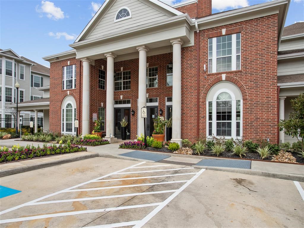 a parking lot in front of a brick building with white columns