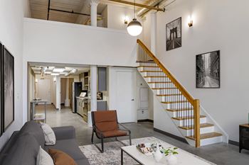 a living area with a staircase and a living room with a couch and a table at Highland Mill Lofts, Charlotte