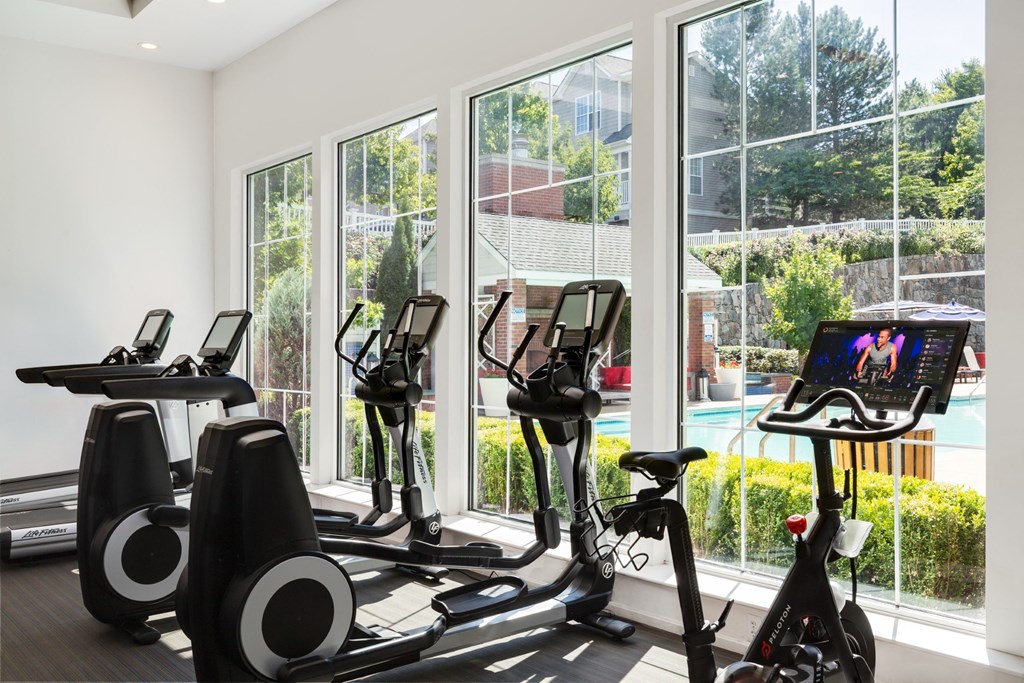 a gym with exercise equipment and windows overlooking a pool at Residences at Stevens Pond, Massachusetts