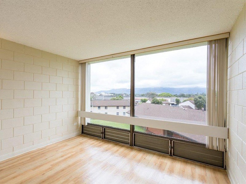 an empty living room with a large window and wood floors at Palms of Kilani Apartments, Wahiawa, 96786