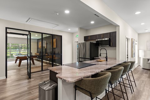 A modern kitchen with a marble countertop and a dining table with chairs.