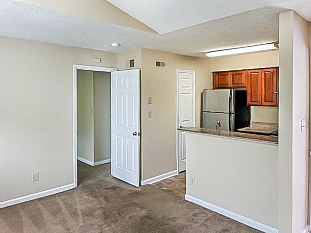 an empty room with a kitchen and a refrigerator