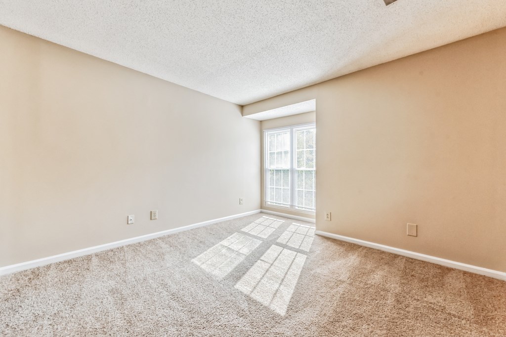a spacious living room with carpet and a window