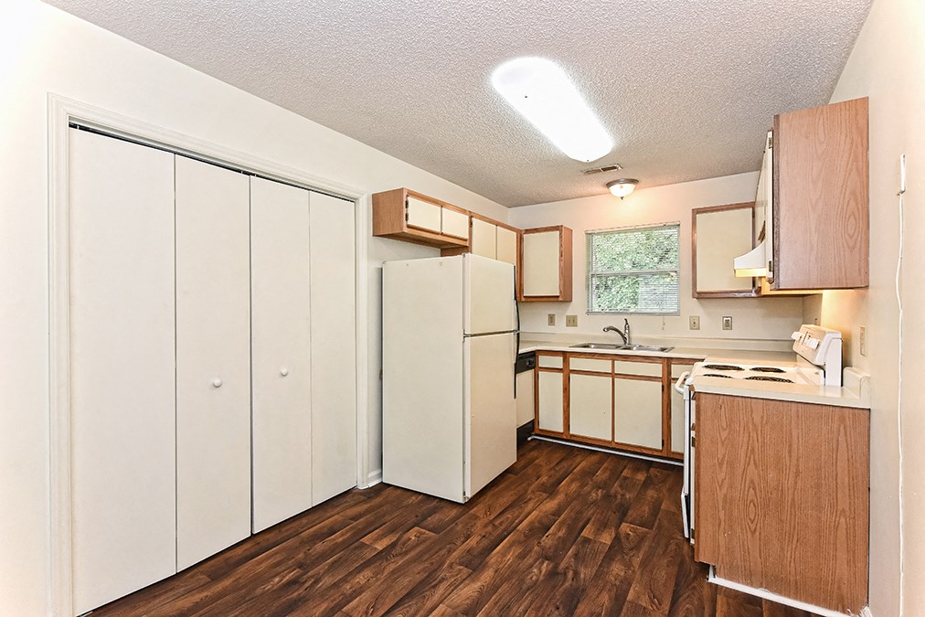 A kitchen with white appliances and wooden floors.