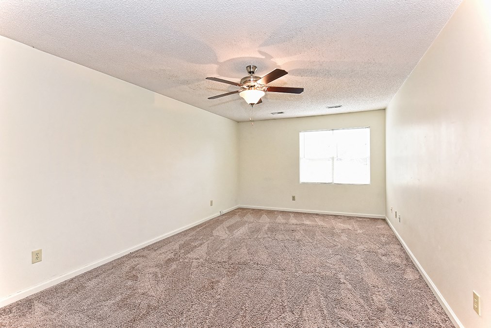 A room with a ceiling fan and carpeted floor.