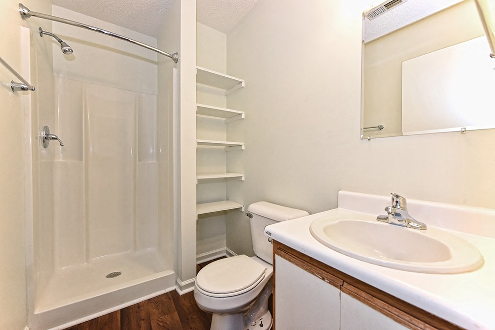 A white bathroom with a toilet, sink, and shower.