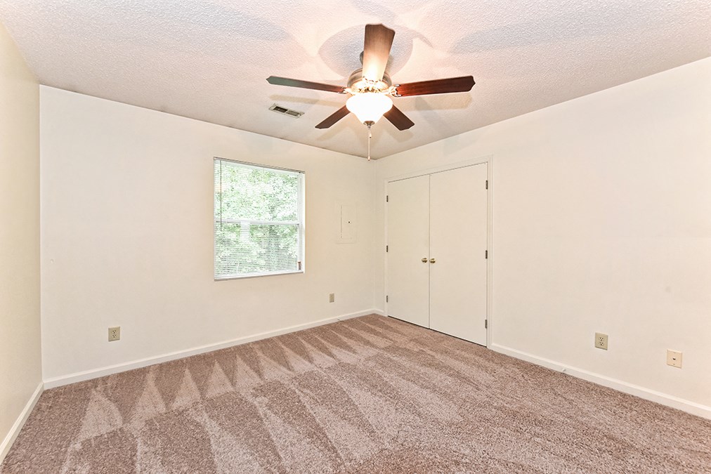A room with a ceiling fan and carpeted floor.