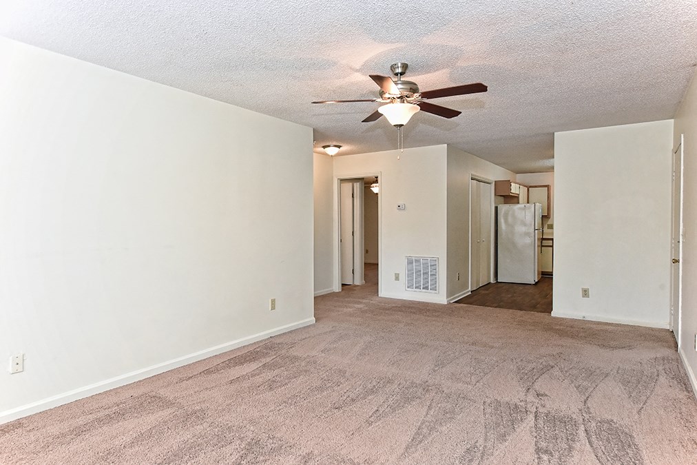 A room with a ceiling fan and carpeted floor.