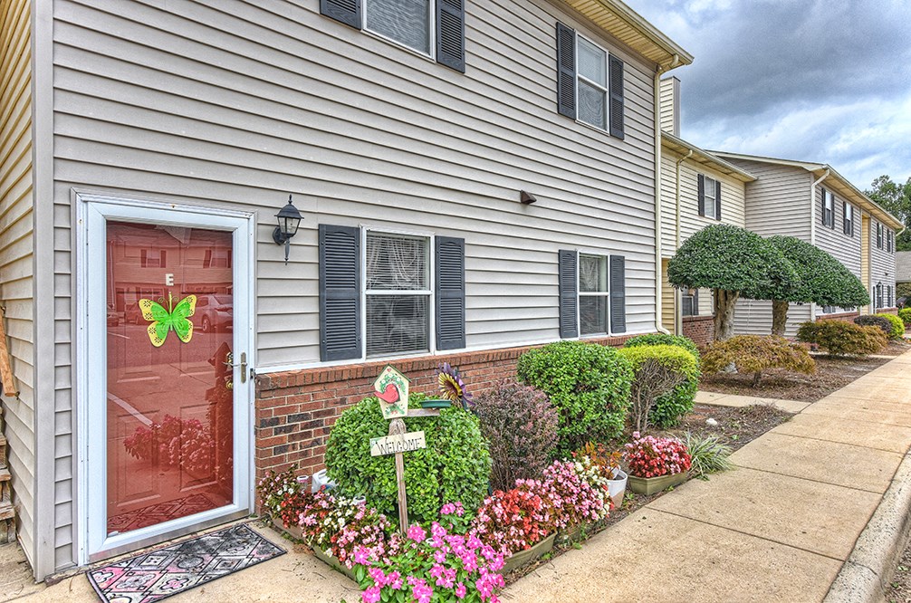 A house with a red door and a sign that says "Welcome".