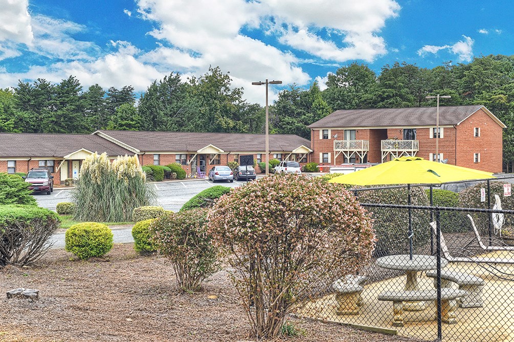 A sunny day at a residential complex with a playground and picnic tables.