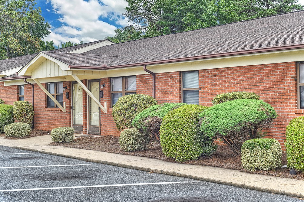 A red brick building with a brown roof and a parking lot in front.