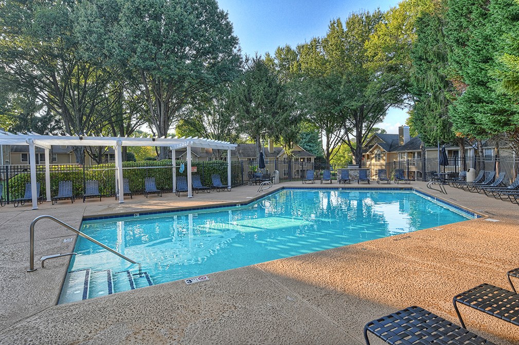 a resort style pool with chairs and trees around it