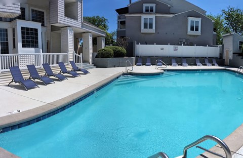 a swimming pool with blue chairs next to a house