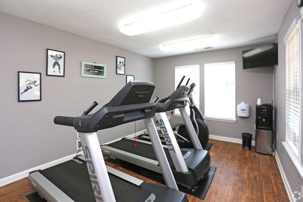 A treadmill in a room with a grey wall and a window.
