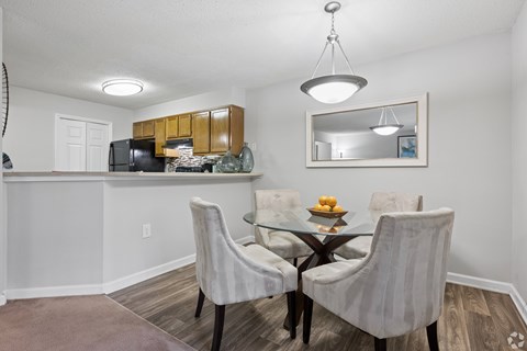 A dining room with a glass table and four chairs.