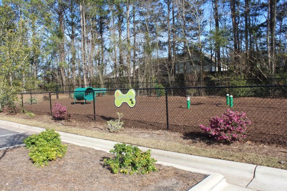 a fenced in area with playground equipment and trees