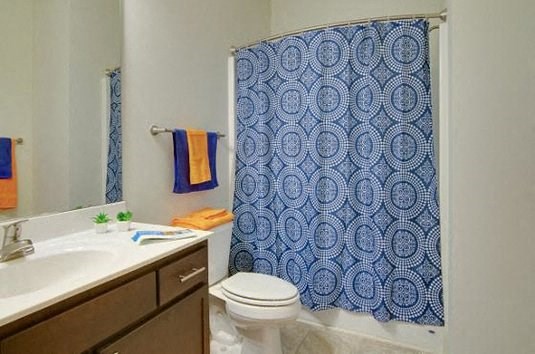 a bathroom with a blue shower curtain and a toilet and sink