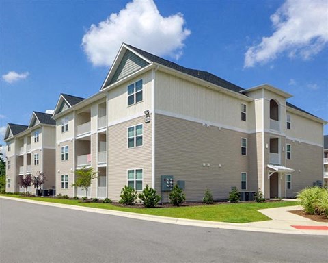 A large apartment building with a parking lot in front.
