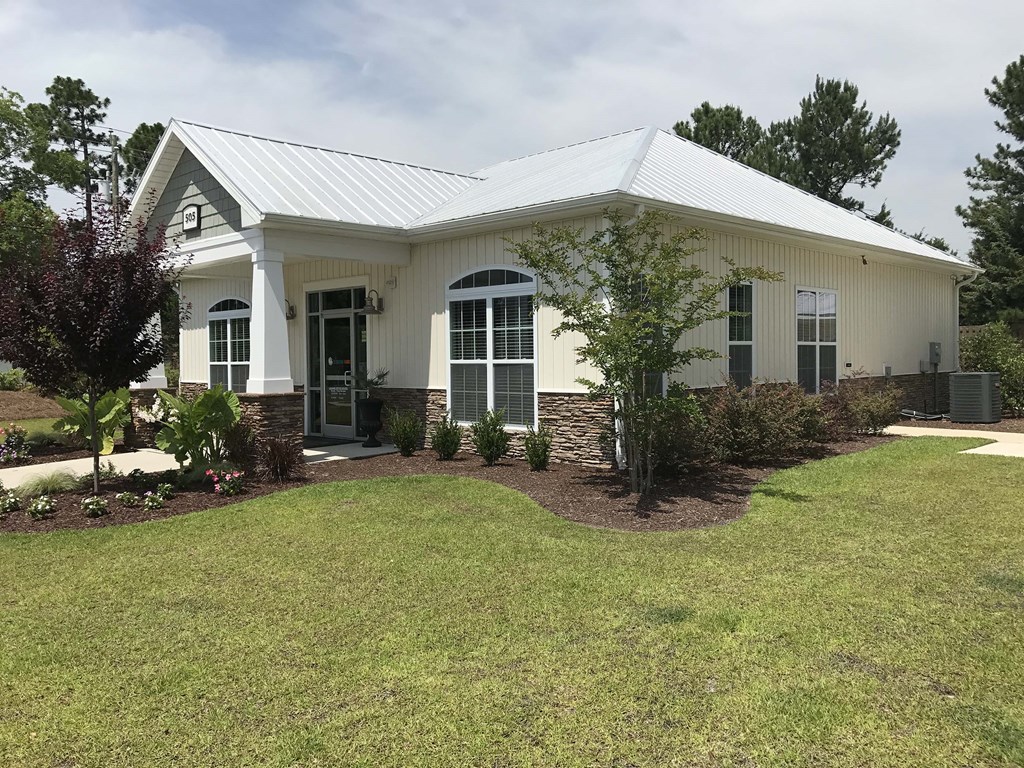 a white house with a green lawn and trees