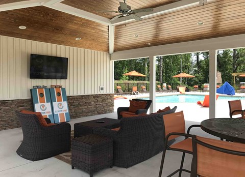 A patio with a television, chairs, and a pool.
