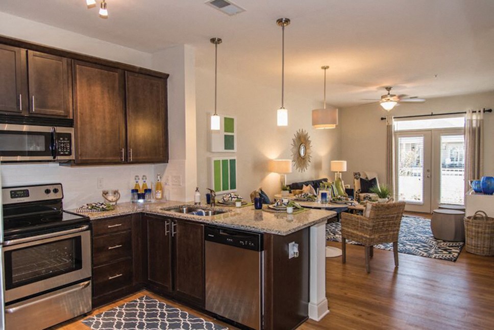 a kitchen with wooden cabinets and a living room with a table and chairs