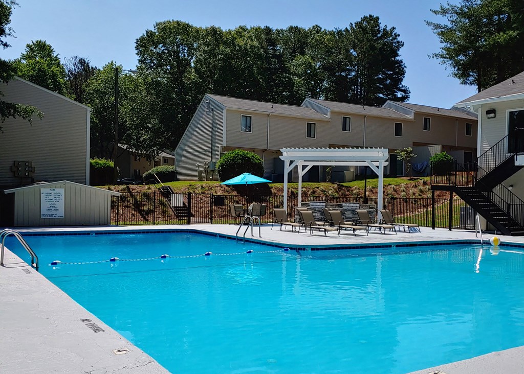 a large swimming pool with tables and chairs next to a building