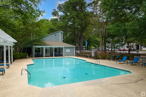 A small pool surrounded by trees and a building.