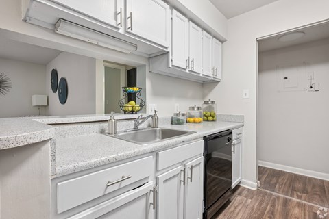 A kitchen with white cabinets and a marble countertop.