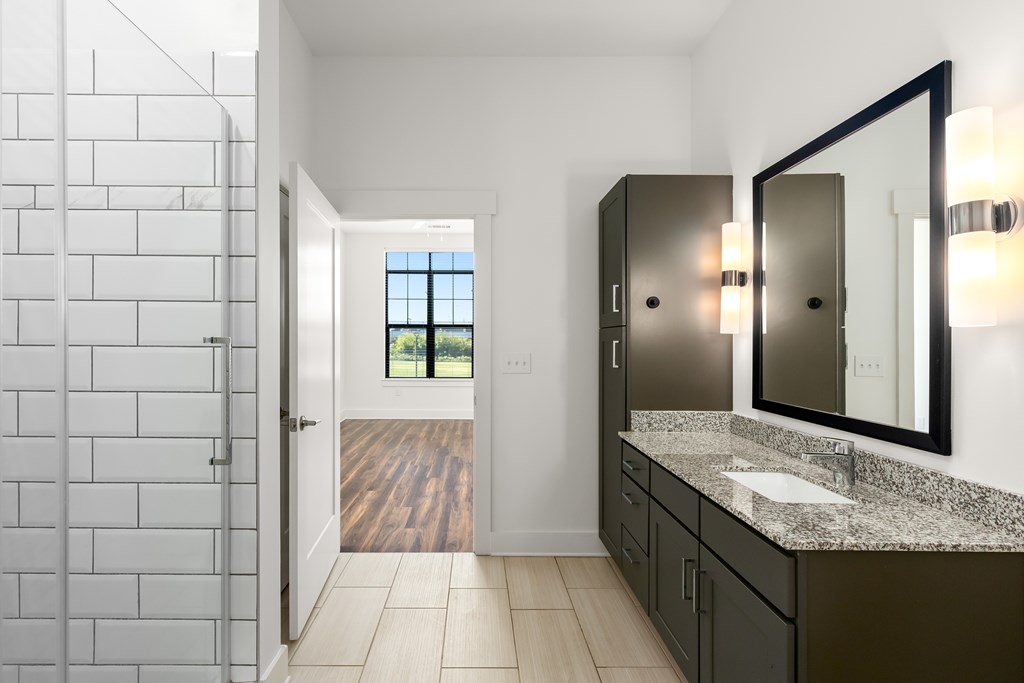 A bathroom with a white tiled shower area and a marble counter top.