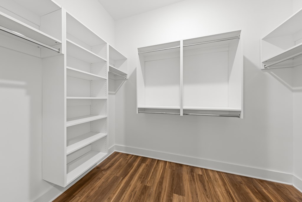 A white walk in closet with shelves and a sliding door.